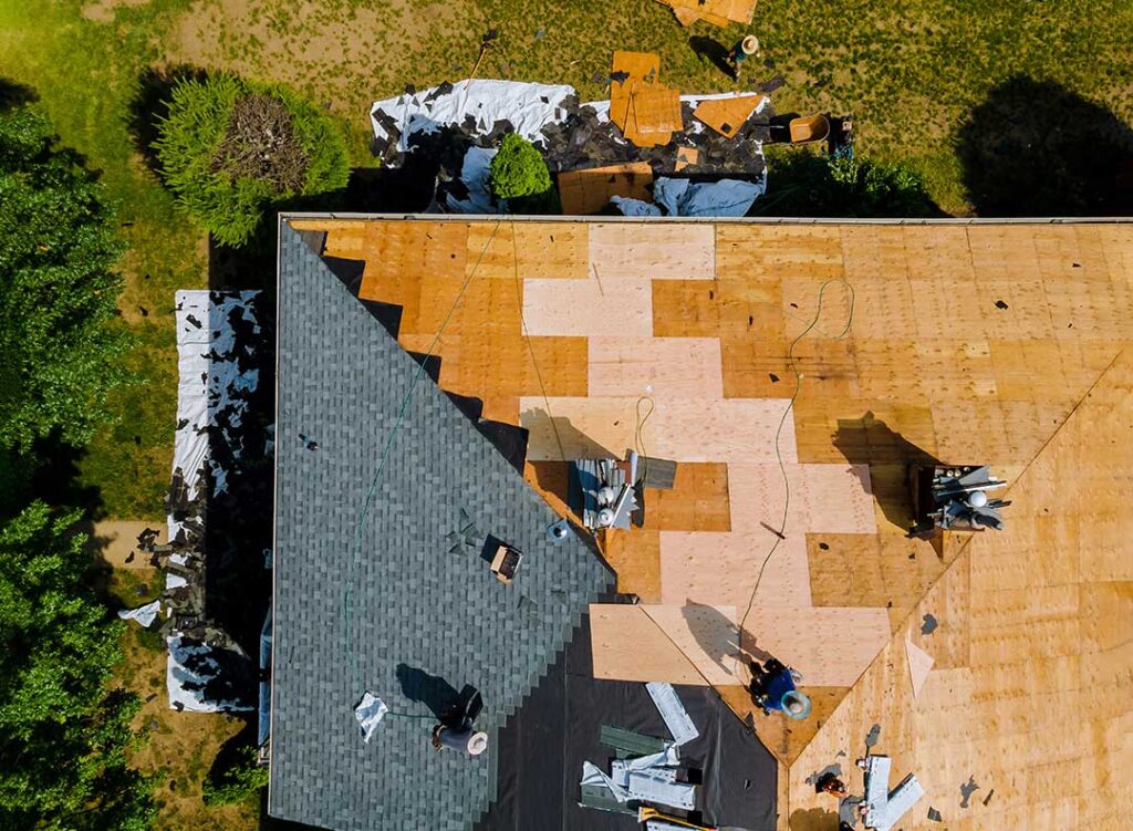 Homeowner photographs damaged shingles and an interior ceiling leak with a phone and written notes.