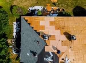 Homeowner photographs damaged shingles and an interior ceiling leak with a phone and written notes.