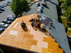 Solar panels mounted on a pitched shingle roof beside trees, gutters, and a roof access area.