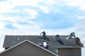 A homeowner views moss patches and dark algae streaks on shaded asphalt shingles from the ground.