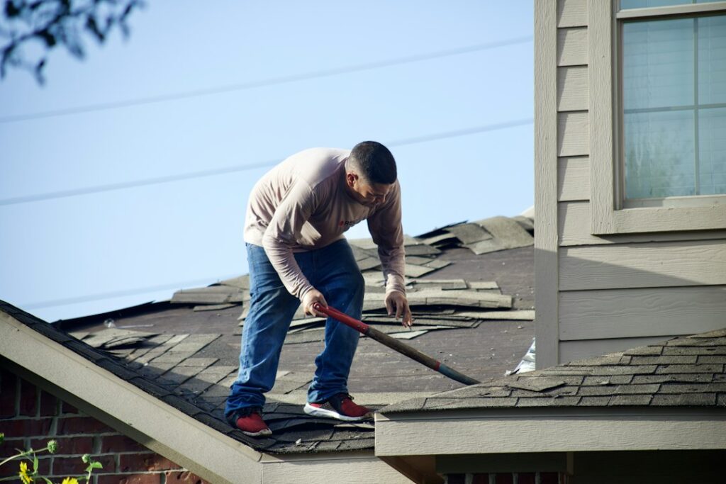 A homeowner observes roof shingles and gutters from the ground while checking for storm damage and seasonal wear.